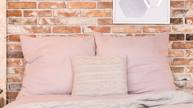Bed with pillows to represent DIY sweater pillows.