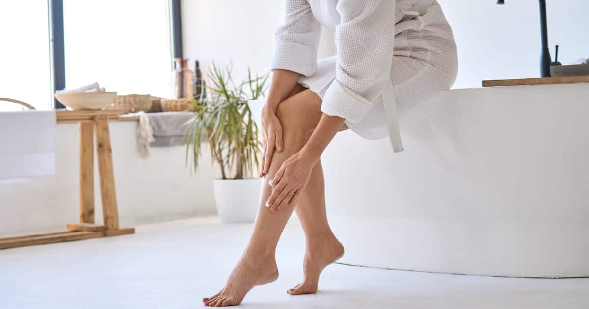 View of woman's lower legs as she applies lotion.