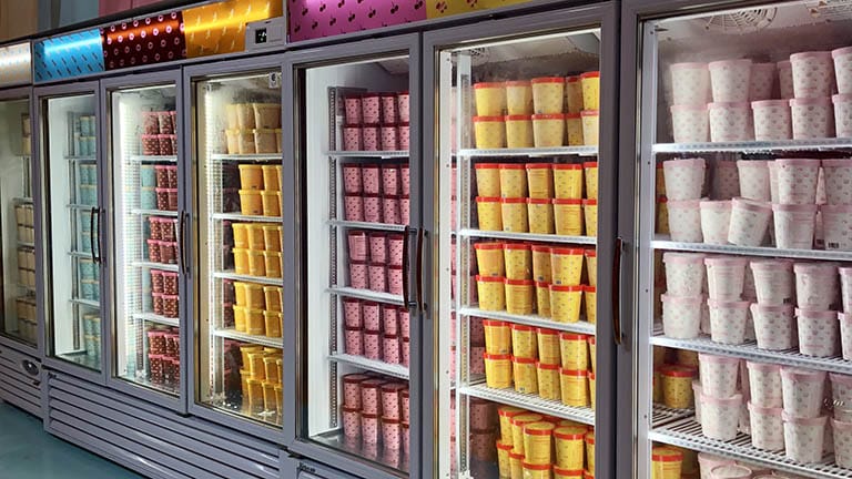 Ice cream containers inside refrigerator at store.