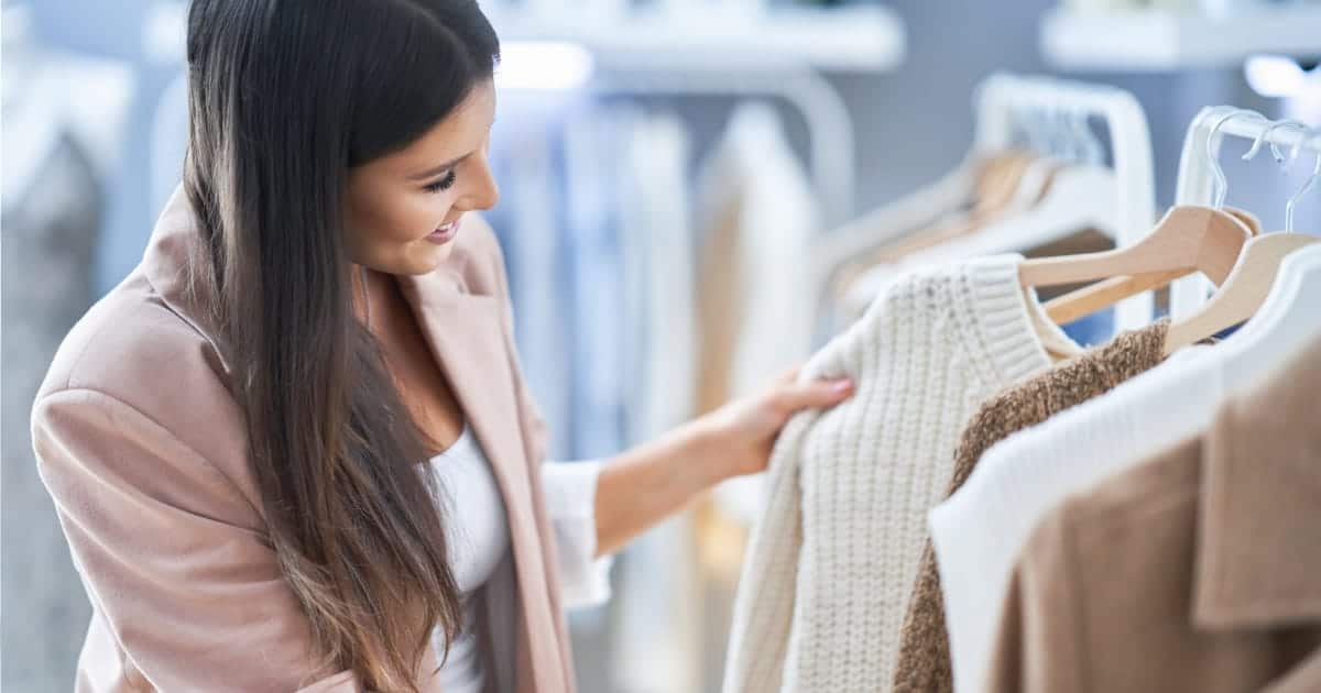 Close-up of woman browing clothes on rack in store like Bloomingdale's.
