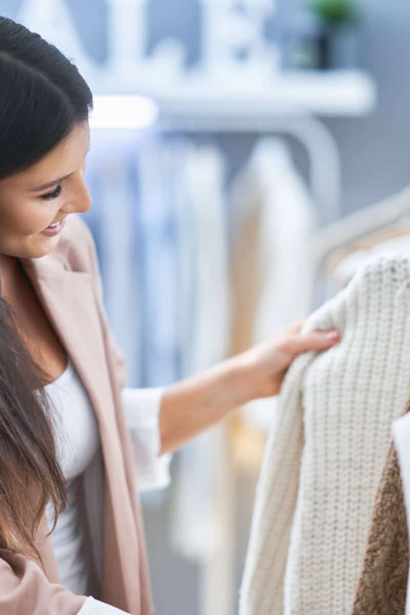 Close-up of woman browing clothes on rack in store like Bloomingdale's.