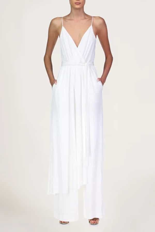 Woman wearing white satin jumpsuit by Halston.