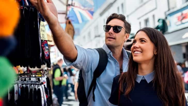 Couple enjoying cheap shopping in London at Portobello Road Market.
