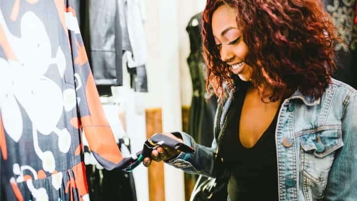 Woman looks at price tag on garment to represent shopping at Saks Fifth Avenue's outlet store.