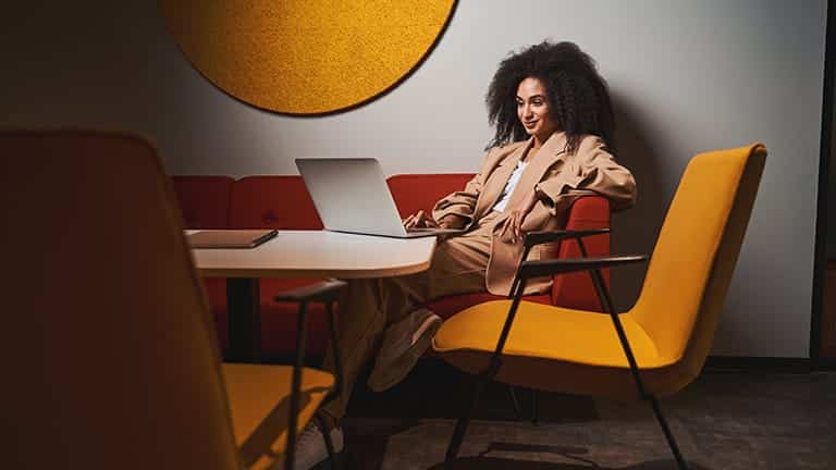 Stylish woman sits in lounge with laptop.