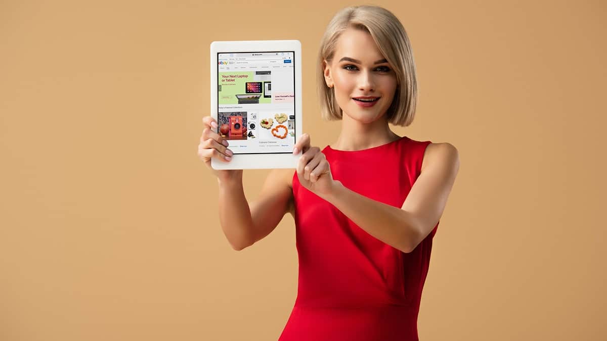 Woman holding up tablet with ebay, one of the most popular clothing auction sites
