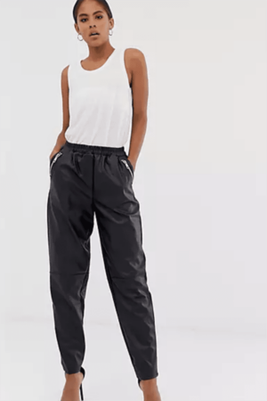 Woman wearing leather joggers and tank top.
