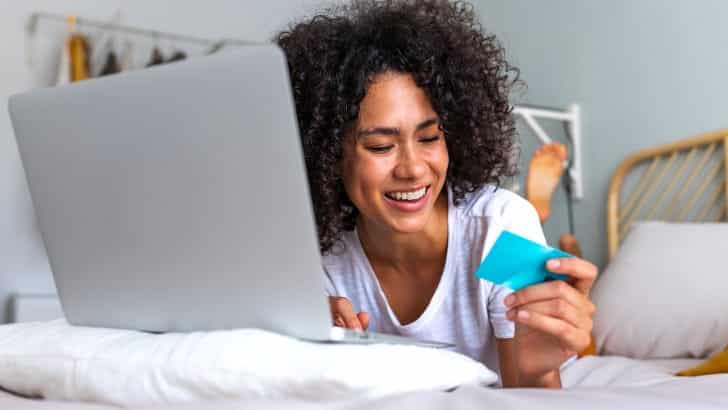 Smiling woman shopping online to represent why shop Amazon.