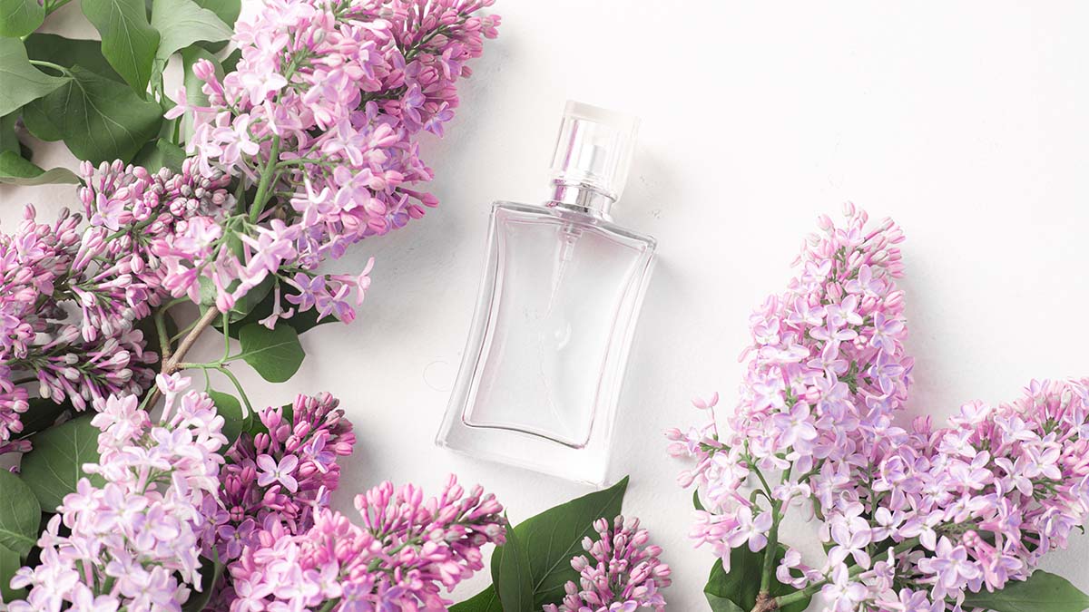 Generic budget perfume against white background, surrounded by lilacs.