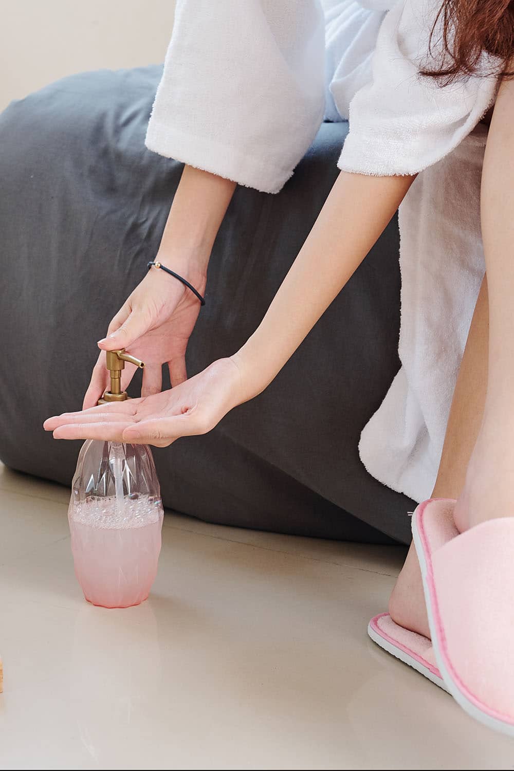 Woman applies body moisturizer at home.