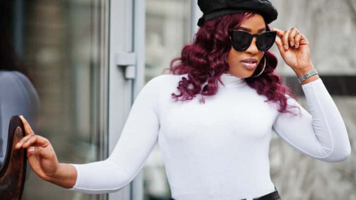 Fashionable plus size woman wearing sunglasses and hat outside.