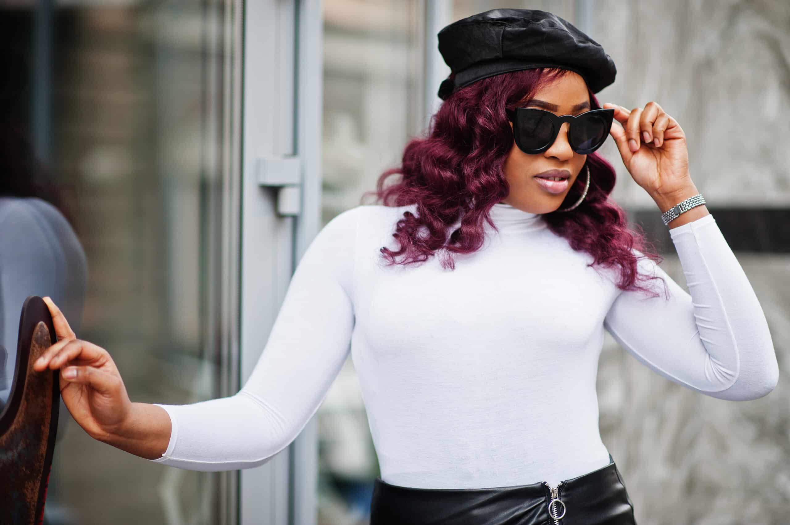Fashionable plus size woman wearing sunglasses and hat outside.