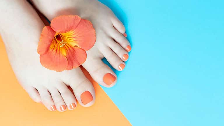 Orange pedicure with orange and blue background.