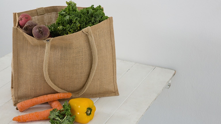 Fresh vegetables inside reusable grocery bag.