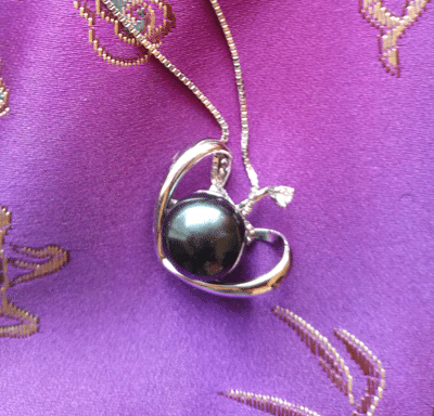 black pearl pendant on purple fabric