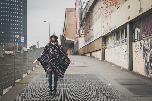 woman wearing poncho and skinny pants