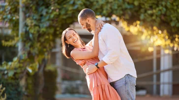 Couple smiles and hugs on spring date.