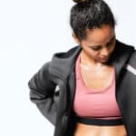 Woman wearing sports bra outfit with cropped jacket.
