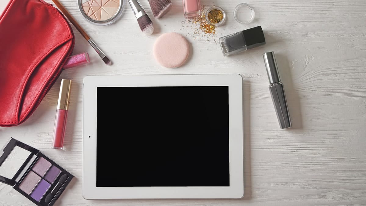 Laptop surrounded by makeup on table top