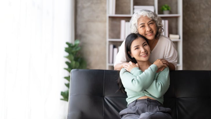 Mother and adult daughter hug and smile.