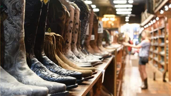 Cowboy boots, trend shoes for fall, on rack in shoe store.