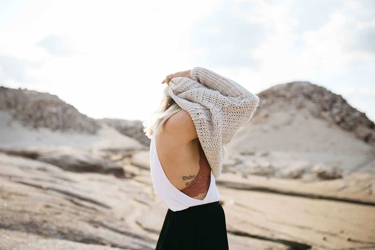 woman pulling sweater over her head