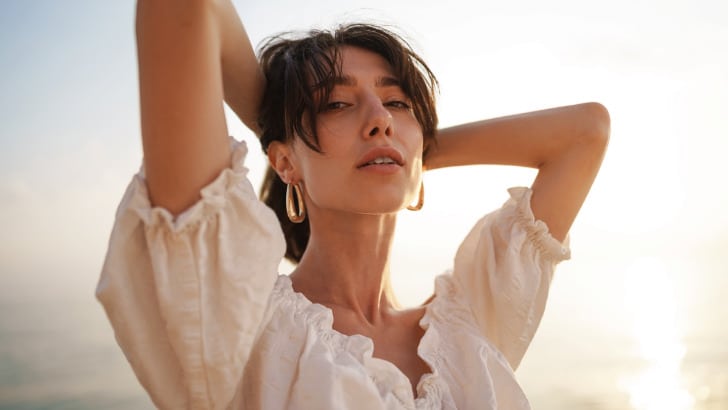 Woman holds hair off neck in summer.