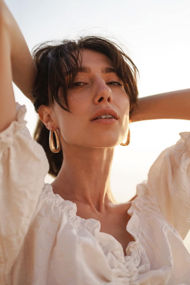 Woman holds hair off neck in summer.