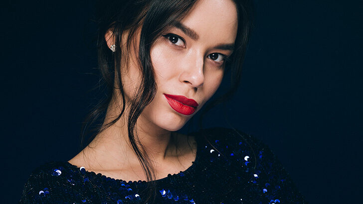 Close up of woman wearing red lipstick and blue sequin dress.