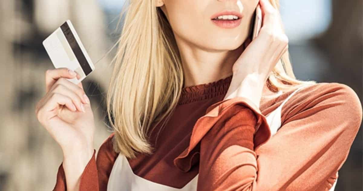Fashionable woman holds up credit card.
