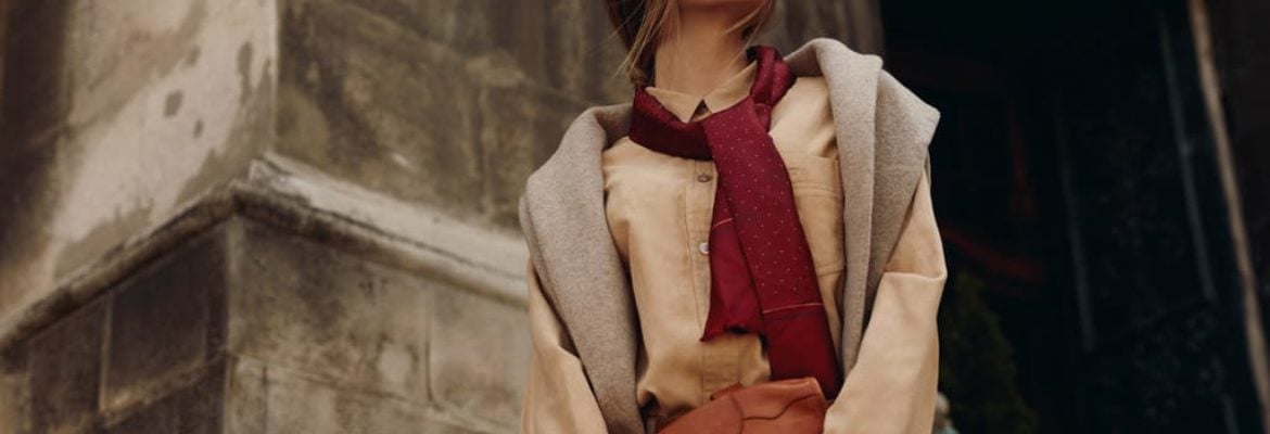 Woman wearing warm-toned layered outfit with scarf.