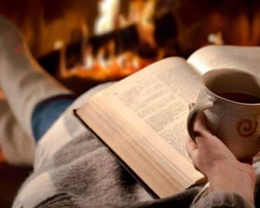 Women lounging by the fire with a blanket and good book
