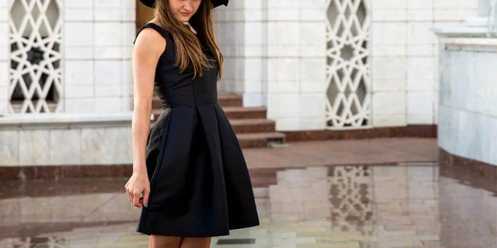 Woman wearing black hat and black fit n flare cocktail dress