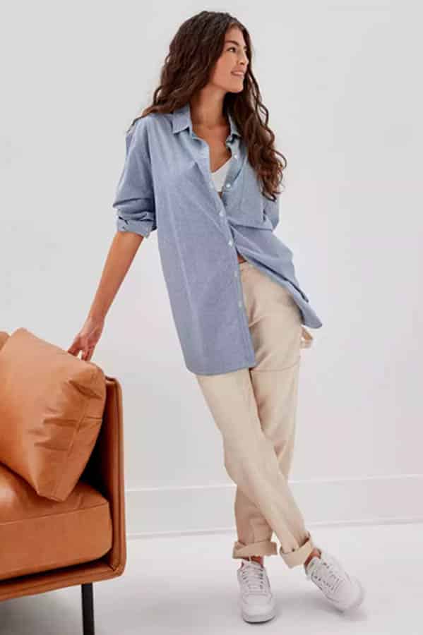 Model wearing oversized button-down top with beige pants.