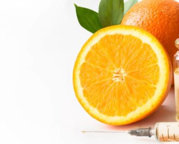 Orange and vial of vitamin C serum