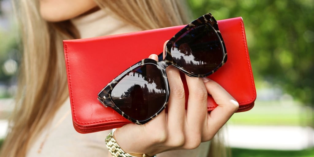 woman holding red wristlet and sunglasses