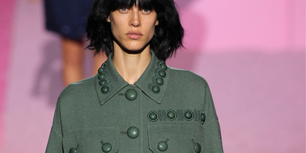 Runway model wearing olive green shirt jacket with buttons