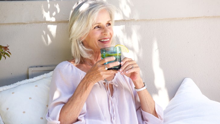 Fashionable older woman sitting outside, smiling.