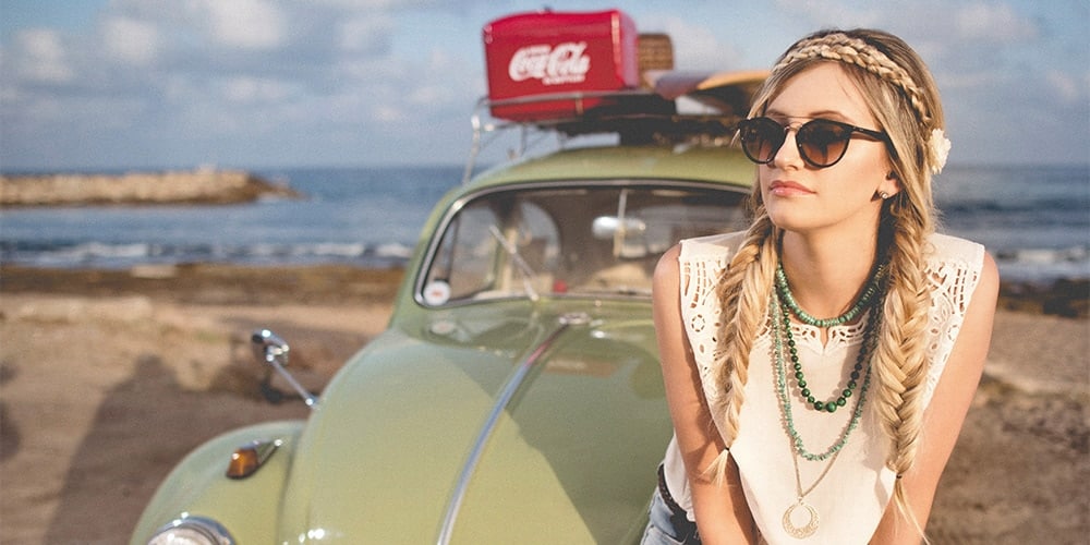 Girl wearing 70s style clothes sitting on VW bug