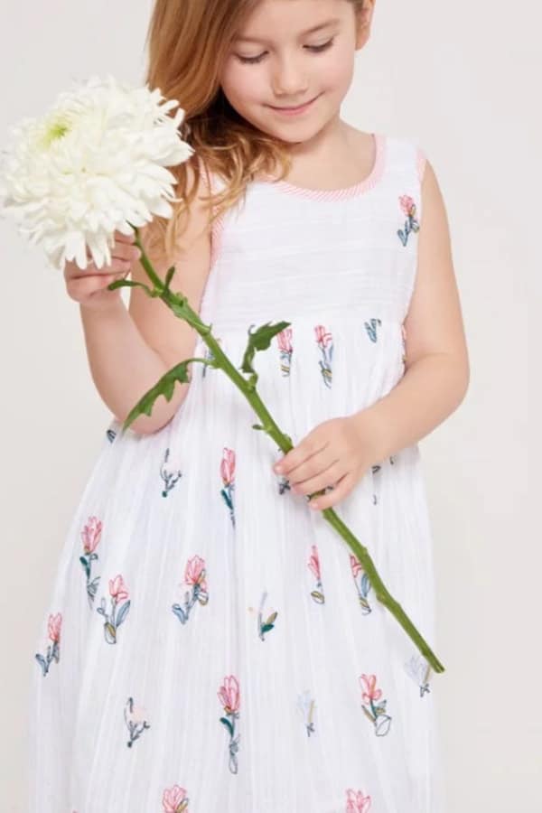 Young girl wearing white dress with floral pattern.