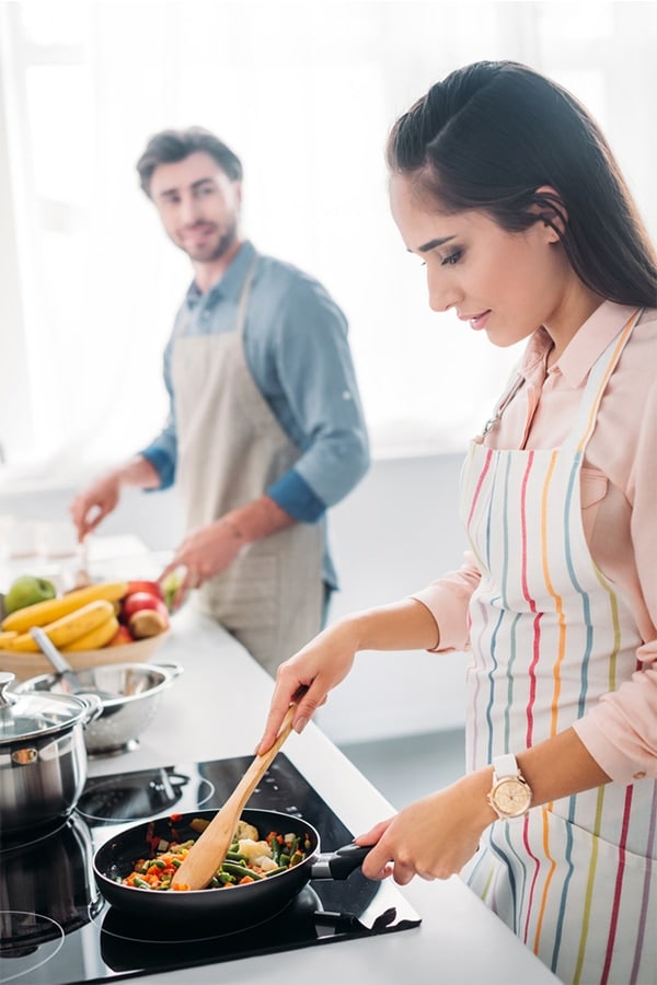 Two adults cooking in kitchen.