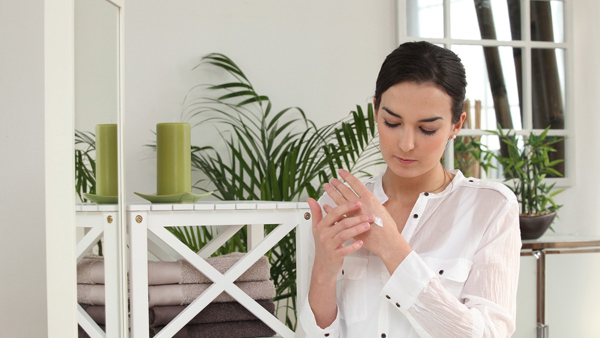 Woman using hand cream on dry skin