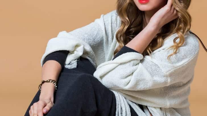 Woman wearing fringe cape sitting down.