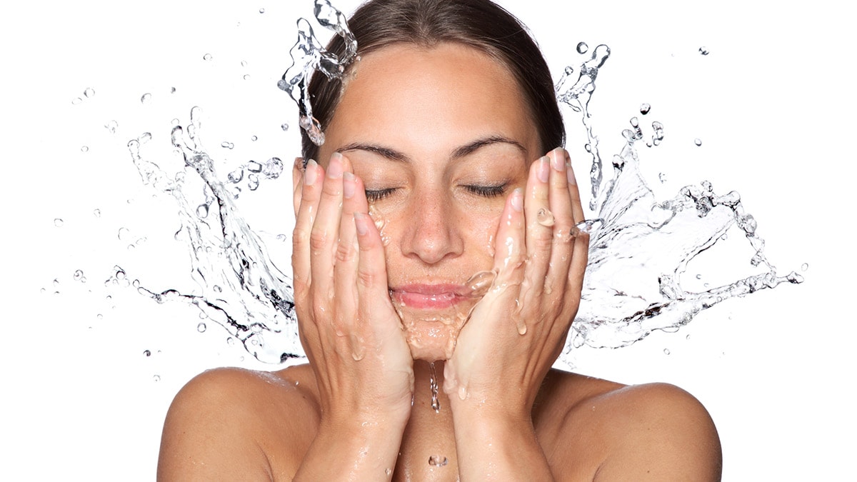 Woman washing her face with water