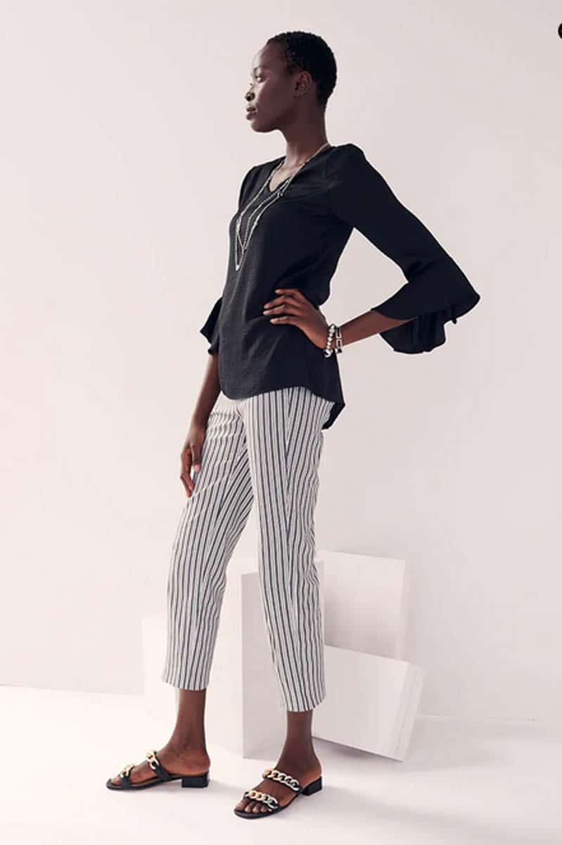 Model wears black top and striped capri pants.