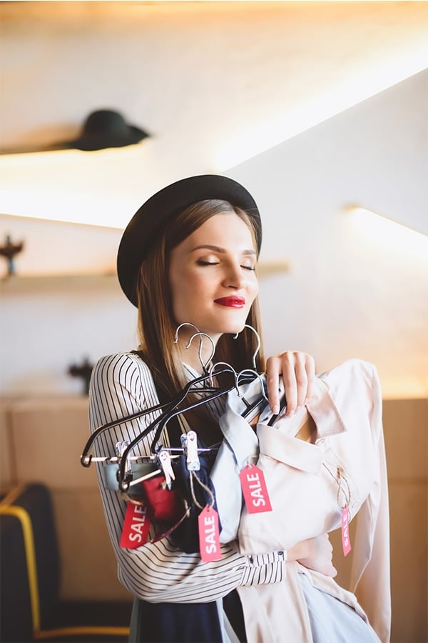 See a Label with the Designer Name Famous Maker? Here's What it Means 1 Woman holding clothes with sales tags