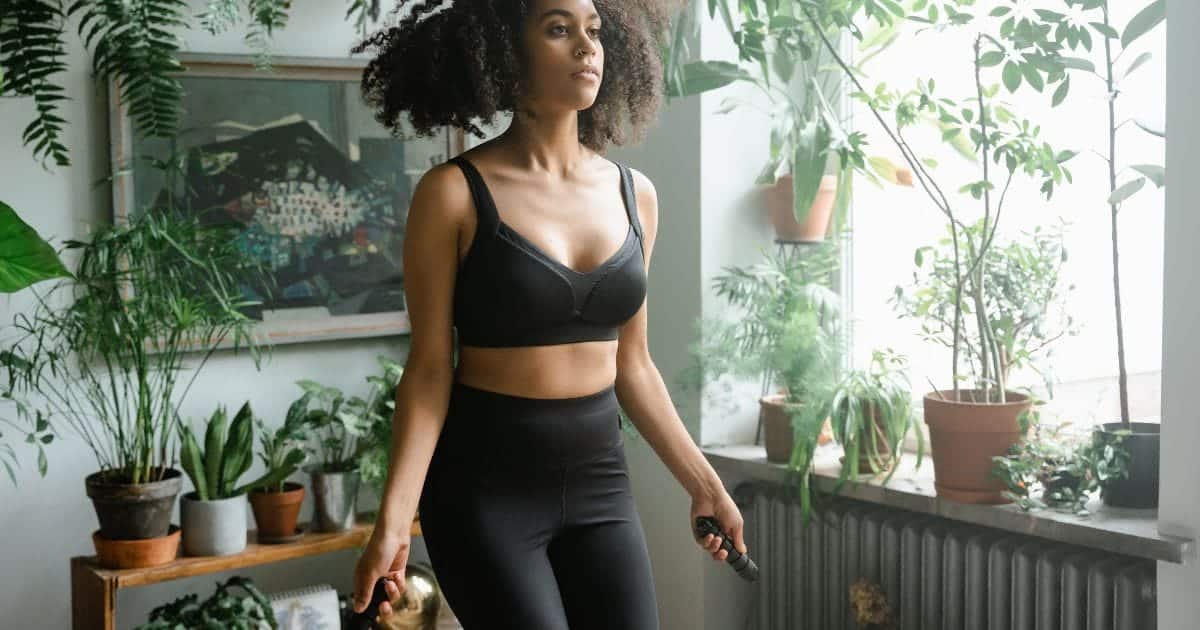 Woman wearing workout clothes jumping rope at home.
