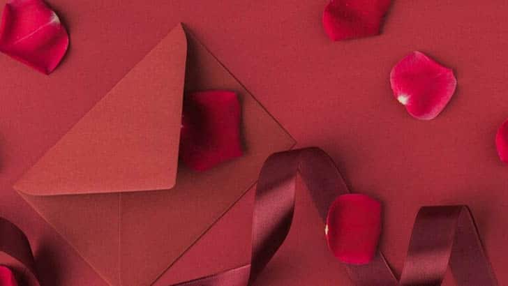 Red card against red background with rose petals.