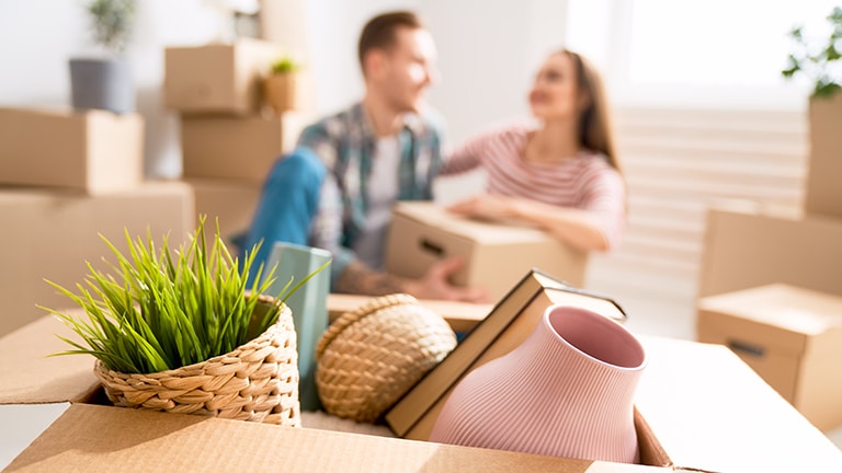 Couple in apartment with boxes to represent apartment decorating.