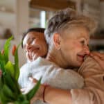 Senior mom hugs adult daughter after receiving Mother's day jewelry gifts.